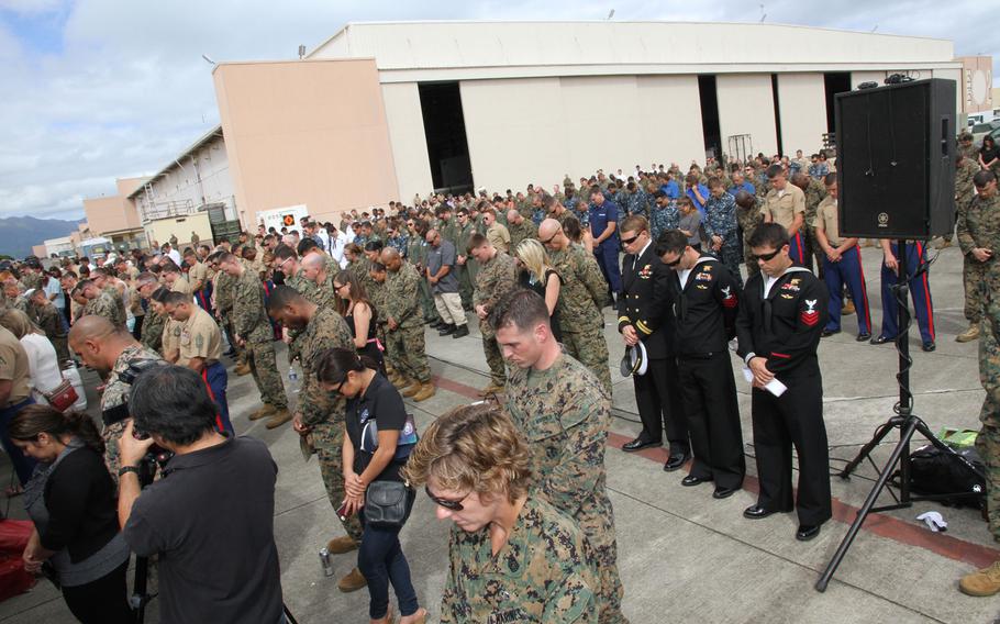 Mourners bow their heads during a prayer at the Friday memorial at Marine Corps Base Hawaii for 12 Marines declared dead after the two helicopters they were in crashed Jan. 14 in Hawaii. Their remains have not been found.