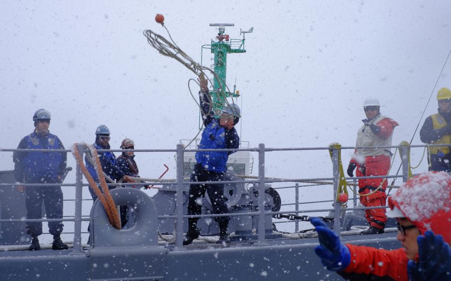 A USS Patriot crewmember throws a heaving line to the pier in Otaru, Japan, on Thursday, Feb. 4, 2016. The Avenger-class mine-countermeasures ship from Sasebo, Japan, is making its first visit to the city.

