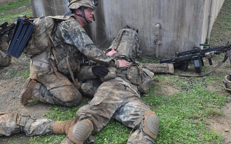 A soldier tends to the wounds of another during a mock raid on a terrorist stronghold during a scenario from Exercise Lightning Forge Feb. 5, 2016, at Marine Corps Training Area Bellows, Hawaii.