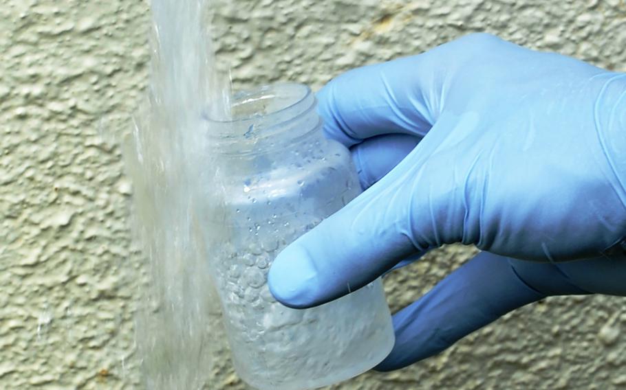 An airman from the 18th Aerospace Medicine Squadron Bioenvironmental Engineering flight collects a water sample from a spigot on Kadena Air Base, Japan, Sept. 23, 2014. Earlier this month, Kadena officials acknowledged using a restricted contaminant after it was detected in waterways in and around the base. 