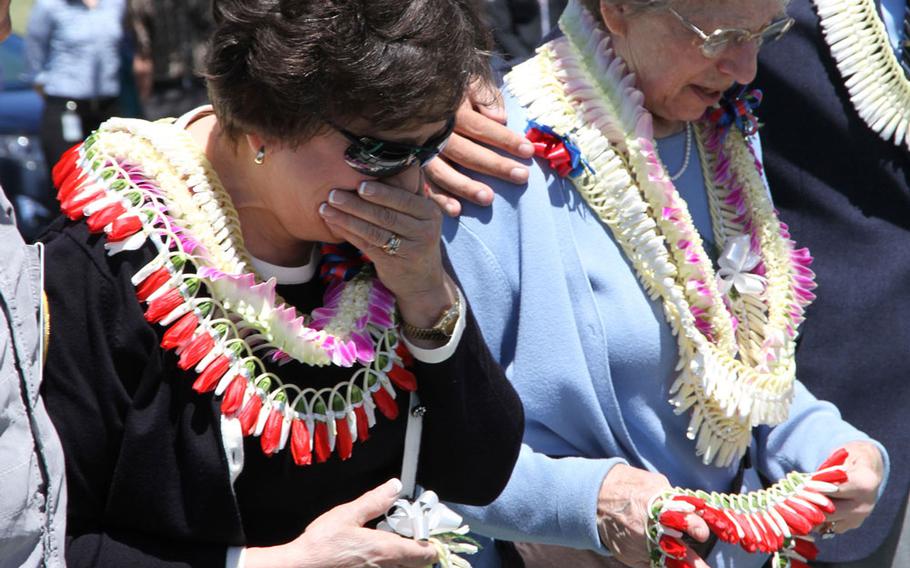 Relatives of Petty Officer 1st Class Vernon T. Luke -- niece Leeann Michalske (right) and Marilyn Gardner, widow of Luke's nephew -- prepare to drop Hawaiian leis onto his lowered casket during a funeral held March 9, 2016, at the National Memorial Cemetery of the Pacific in Honolulu.