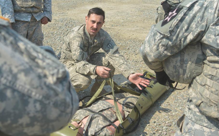 Staff Sgt. Nathan Sanchez, 37, a 3rd Battalion flight medic from Pleasanton, Calif., shows medics how to strap a patient into a stretcher to be hoisted into a hovering helicopter, Wednesday, March 16, 2016, at Rodriguez Live Fire Range, South Korea.