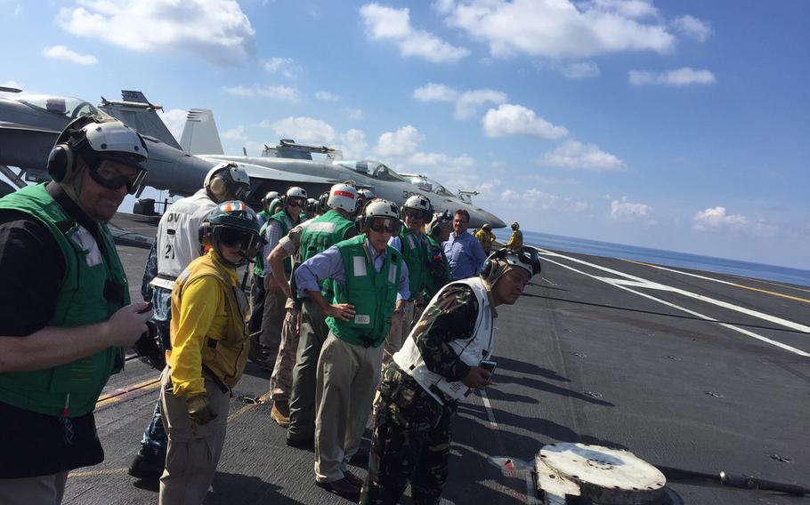 Defense Secretary Ash Carter, center background, without helmet, and others observe carrier launches of F/A-18 Super Hornets aboard the USS John C. Stennis during a sail through the South China Sea Friday, April 15, 2016. 

