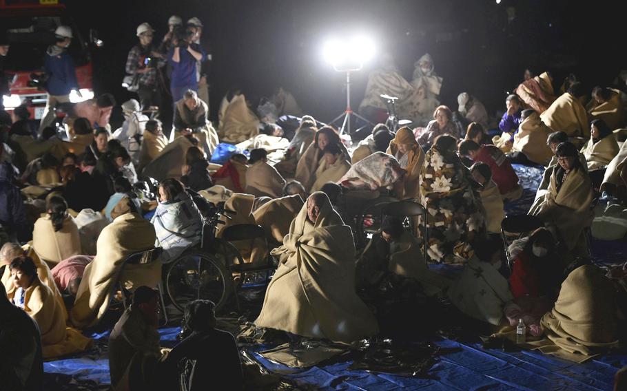 People are seen at a parking lot in Mashiki, Kumamoto Prefecture, Japan, at 1:12 a.m. on Friday after evacuating their homes. 