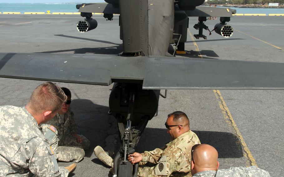 Soldiers take a final look at the rear wheel of an Apache attack helicopter Sunday, April 24, 2016, near downtown Honolulu, Hawaii. Twenty-four Apaches arrived over the weekend via container ship. Maintenance crews spent Saturday preparing them for flight, and by Sunday morning the helicopters were lined up on a pier ready for a trip to Wheeler Army Airfield. 