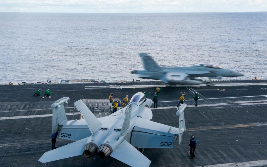An EA-18G Growler launches while sailors taxi another Growler to an adjacent catapult on the USS John C. Stennis flight deck on June 5, 2016, in the South China Sea.