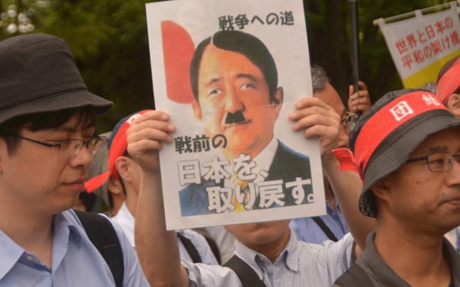 A Japanese protester displays a sign at a rally June 19, 2016, in Tokyo, indicating his displeasure with the Abe administration's decision to expand the role of the Japanese Self Defense Force.


