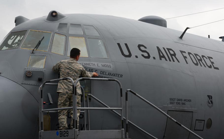 Staff Sgt. George Harlan, 374th Aircraft Maintenance Squadron flying crew chief, unveils the new commander's name, Col. Kenneth Moss, on the 374th Airlift Wing's flagship aircraft during the official wing change of command at Yokota Air Base, Japan, on Friday, June 24, 2016. Moss took command from Col. Douglas DeLaMater. 