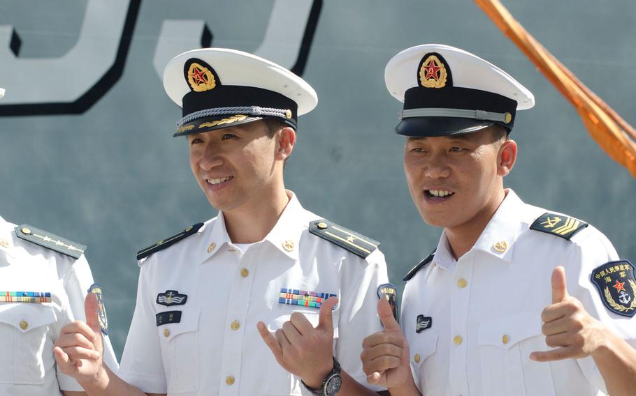 Chinese navy officers make the Hawaiian popular "shaka" (or "hang loose") gesture for visiting reporters July 8, 2016, while standing beside China's guided-missile destroyer Xian, docked at Joint Base Pearl Harbor-Hickam, Hawaii, for the Rim of the Pacific exercise.
