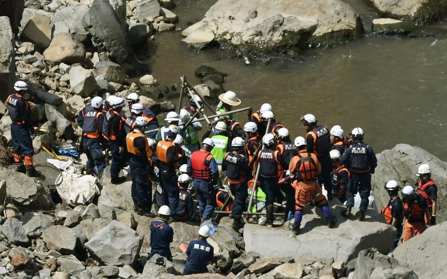 Police officers and firefighters work to retrieve a wrecked car that may hold the final victim of two deadly earthquakes that hit southern Japan nearly four month ago from a riverbank in Minamiaso, Kumamoto, southern Japan, Wednesday, Aug. 10, 2016. Japanese media say the vehicle is buried in sand and rocks down the river from a bridge that collapsed into a deep gully after the second earthquake. Hikaru Yamato, a 22-year-old student, was driving home when the magnitude 7.3 earthquake struck on April 16. 