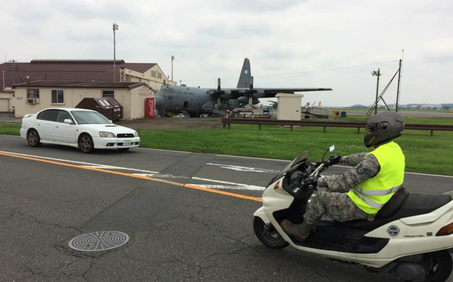 Motorists pass a C-130 Hercules near the flight line at Yokota Air Base, Japan, July 25, 2016.