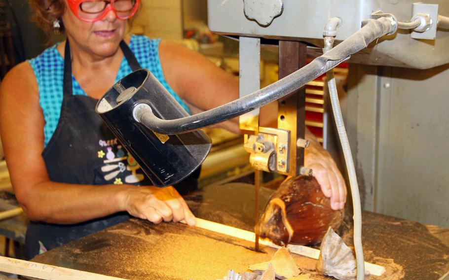 Laura Alves uses a band saw at the Kwajalein Island hobby center to cut coconuts that she decorates as Christmas "snow-conut" characters. Islanders make the most of materials on hand, including the wooden pallets that carry in supplies.
