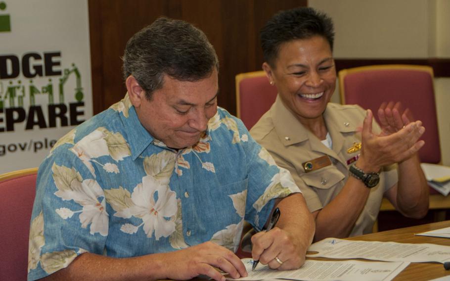 Rear Adm. Bette Bolivar, commander of Joint Region Marianas, applauds Gov. Eddie Calvo during a proclamation signing declaring September as National Preparedness Month on Sept. 4, 2014. Calvo said Thursday that Guam will no longer support a planned U.S. military buildup unless the federal government allows more foreign workers to come to the island. 