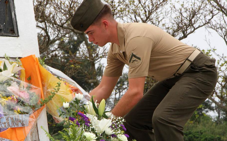 A Marine places flowers at the memorial for acclaimed war correspondent Ernie Pyle, who was killed at this spot on April 18, 1945. 