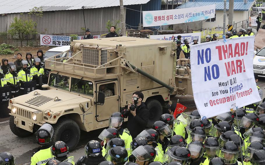 A U.S. military vehicle moves past banners opposing a plan to deploy an advanced U.S. missile defense system called Terminal High-Altitude Area Defense, or THAAD, as South Korean police officers stand guard in Seongju, South Korea, Wednesday, April 26, 2017. 