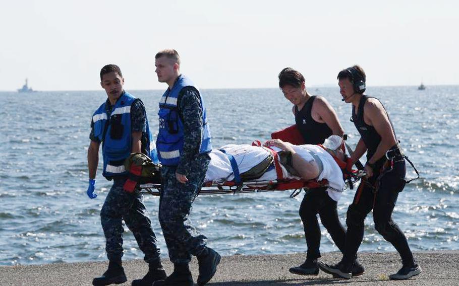 An injured person from the USS Fitzgerald personnel is carried by U.S. and Japanese personnel, at U.S. Naval Base Yokosuka, Japan, on Saturday, June 17, 2017, after the U.S. destroyer collided with a Philippine-registered container ship ACX Crystal.