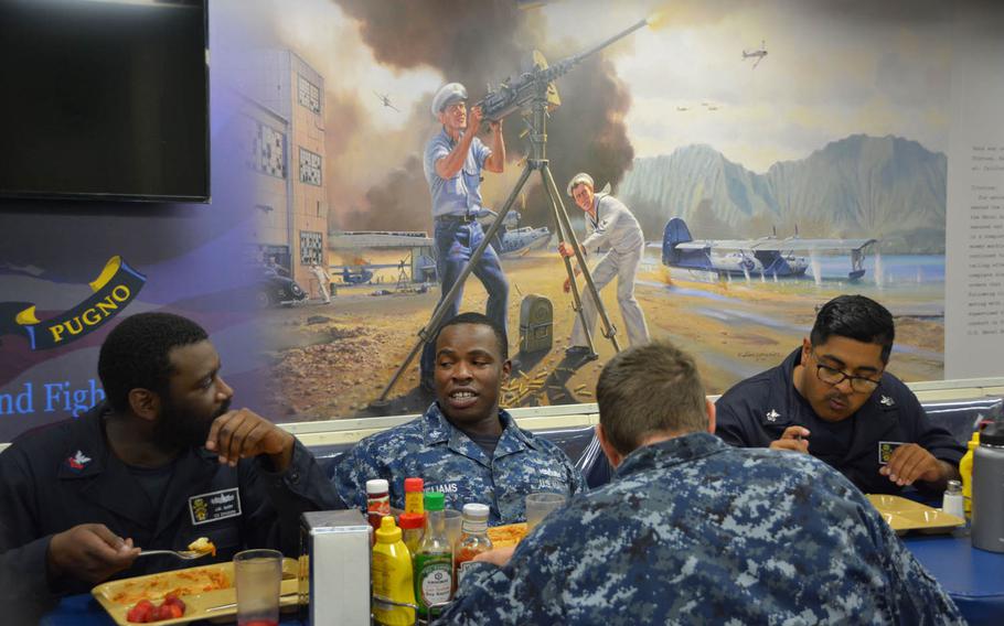 Enlisted sailors eat near a mural in the dining area of the USS John Finn that commemorates the ship's namesake for his actions during the 1941 Japanese surprise attack on Oahu, Thursday, July 13, 2017.