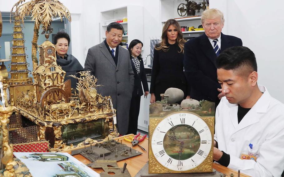Chinese President Xi Jinping, second from left, and his wife Peng Liyuan, first from left, along with U.S. President Donald Trump and first lady Melania Trump watch the repair of relics at the conservation workshop of the Palace Museum in Beijing, Wednesday, Nov. 8, 2017.