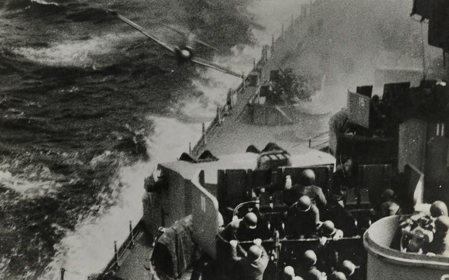 A black-and-white, 1940s-era image of an airplane crashing into a ship at sea.