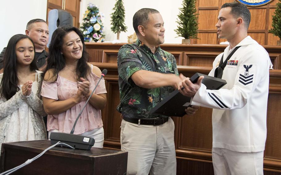Petty Officer 1st Class Anthony Mugavero, assigned to U.S. Naval Base Guam Harbor Patrol, receives a legislative resolution from Sen. Dennis Rodriguez Jr. at the Guam Congress Building on Friday, Dec. 29, 2017.