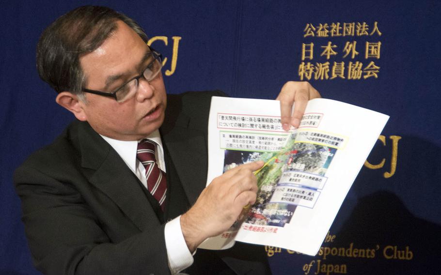 Midorigaoka nursery school headmaster Takehiro Kamiya holds up a map showing official flight paths for Marine Corps Air Station Futenma aircraft, during a press conference in Tokyo, Wednesday, Feb. 14, 2018. 