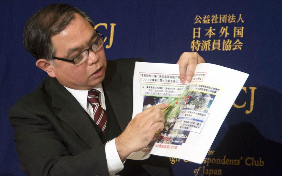 Midorigaoka nursery school headmaster Takehiro Kamiya holds up a map showing official flight paths for Marine Corps Air Station Futenma aircraft, during a press conference in Tokyo, Wednesday, Feb. 14, 2018.