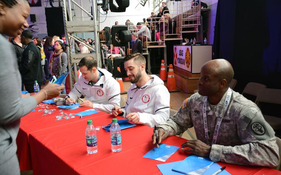 Sgt. Matt Mortensen, left, and his teammate Jayson Terdiman, center, who finished 10th in the doubles luge competition during the Pyeongchang Olympics, and former bobsledder and silver medalist Lt. Col. Garrett Hines sign autographs during Winterfest at Yongsan Garrison in Seoul, South Korea, Monday, Feb. 19, 2018. 