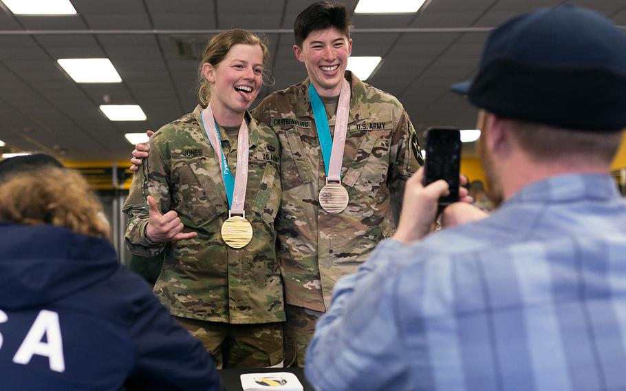 Second Lt. Hannah Jones, 2nd Battalion, 20th Field Artillery Regiment and Sara Cratsenburg pose with Paralympian Noah Elliott's gold and bronze medals as Paralympian Jimmy Sides takes the photo at Camp Casey, South Korea, Saturday, March 17, 2018.