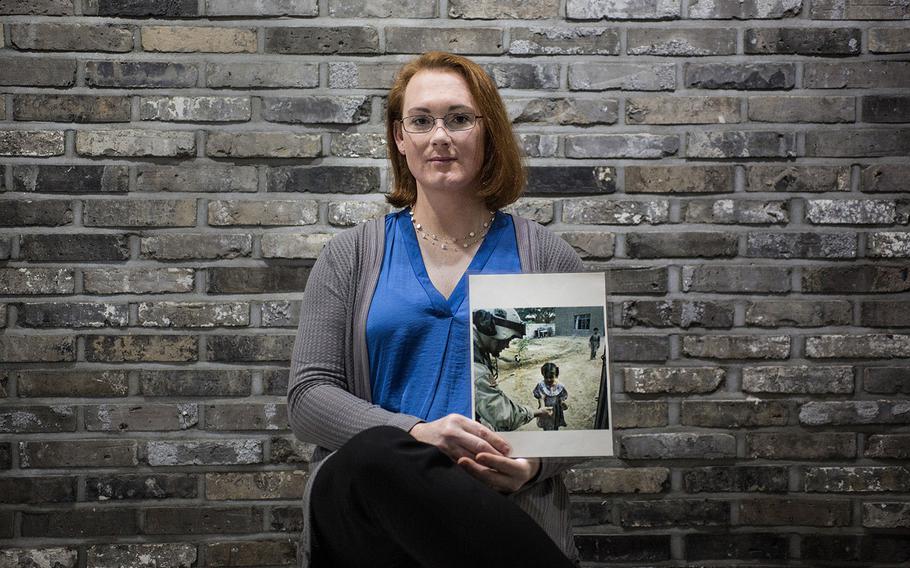 Chief Warrant Officer 3 Lindsey Muller poses for a photo while holding an image from her tour to Iraq on Thursday, March 29, 2018. 