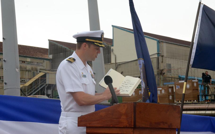 Cmdr. Micah Murphy, commanding officer of the USS John S. McCain, holds a signed copy of one of John McCain III’s books.


