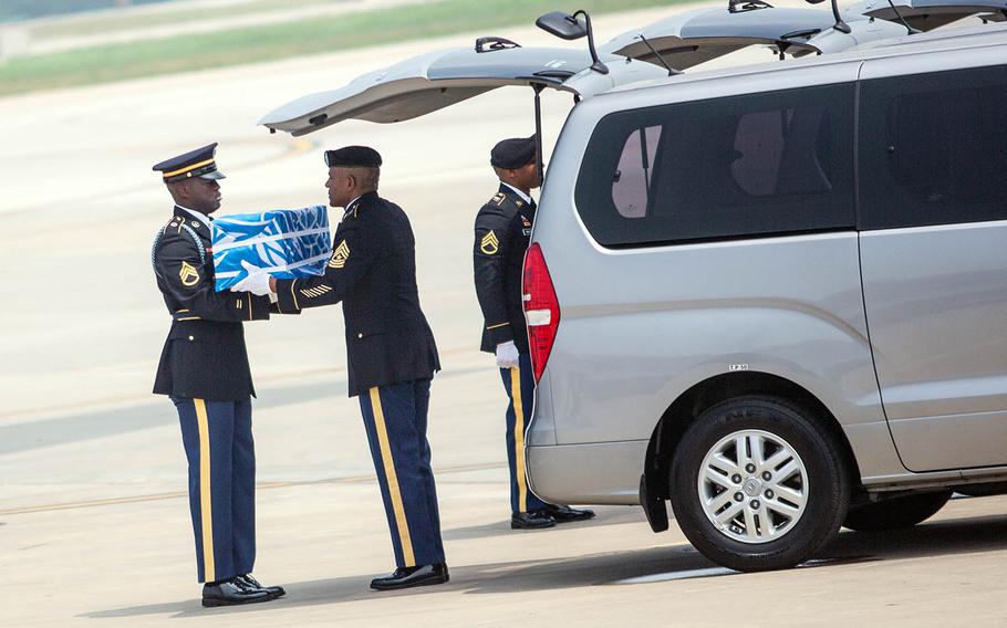 Staff Sgt. Jamil Green, left, hands over the final case of remains at Osan Air Base, South Korea, Friday, July 27, 2018.