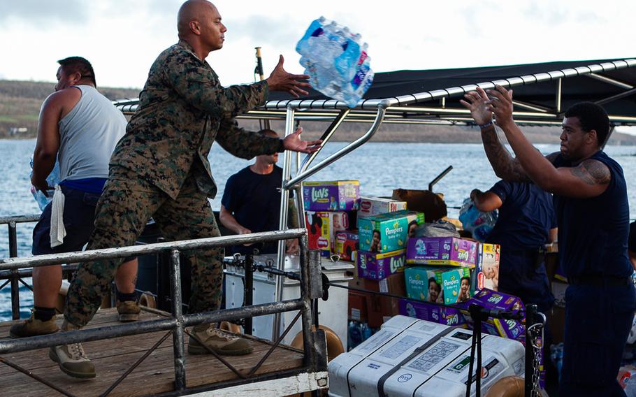 Gunnery Sgt. Angel Ignacio, the battalion gunnery sergeant with Combat Logistics Battalion 31, catches a package of bottled water from a Coast Guard member aboard the U.S. Coast Guard cutter Washington while delivering food and supplies to citizens of Tinian, Oct. 29, 2018.
