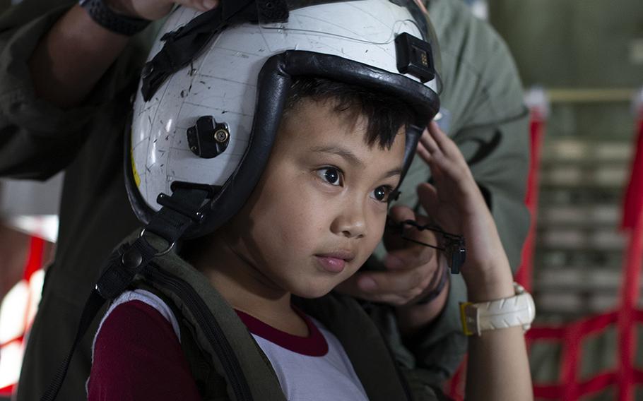 Marine Corps Sgt. Alberto Ruiz II helps a student try on flight equipment for KC-130 crew members during the Balikatan exercise at Clark Air Base, Philippines, April 6, 2019. 