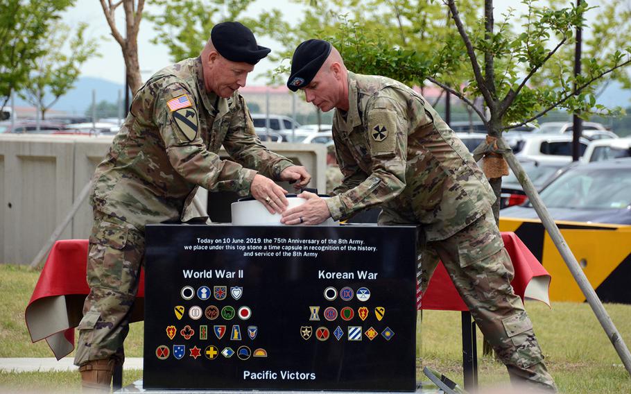Eighth Army commander Lt. Gen. Michael Bills, left, and Command Sgt. Maj. Jason Schmidt place a time capsule inside a memorial stone on Camp Humphreys, South Korea, Monday, June 10, 2019.