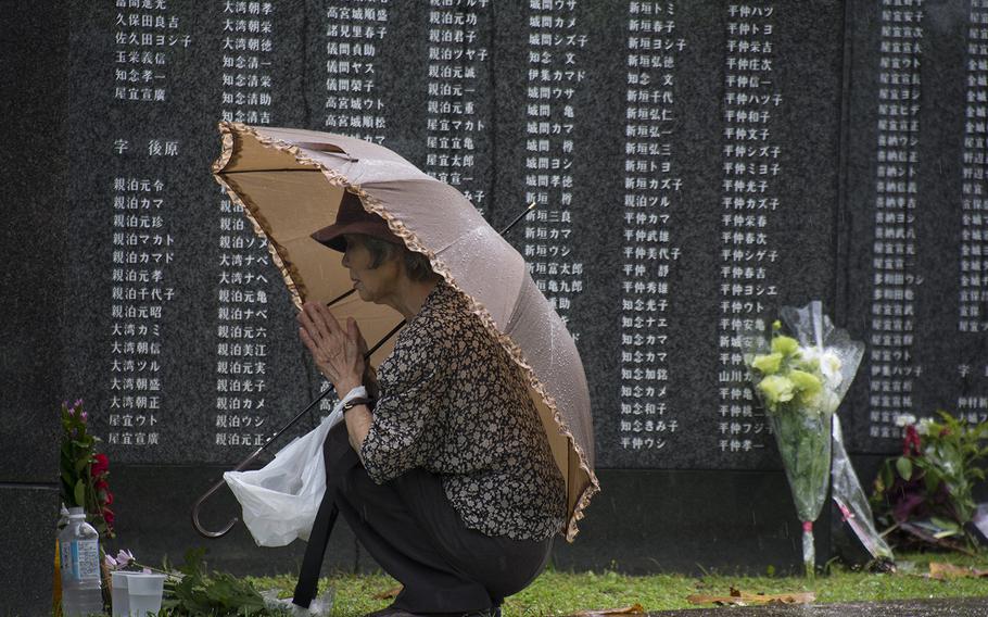 A visitor prays in front of the Cornerstone of Peace monuments at Okinawa Peace Memorial Park during the Irei no Hi ceremony, Sunday, June 23, 2019.