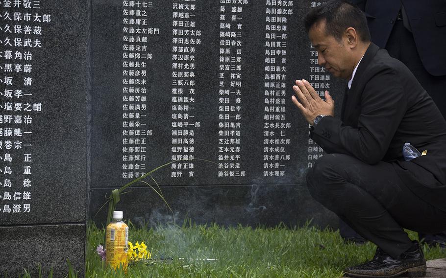 A man prays in front of the Cornerstone of Peace at Okinawa Peace Memorial Park, Sunday, June 23, 2019.