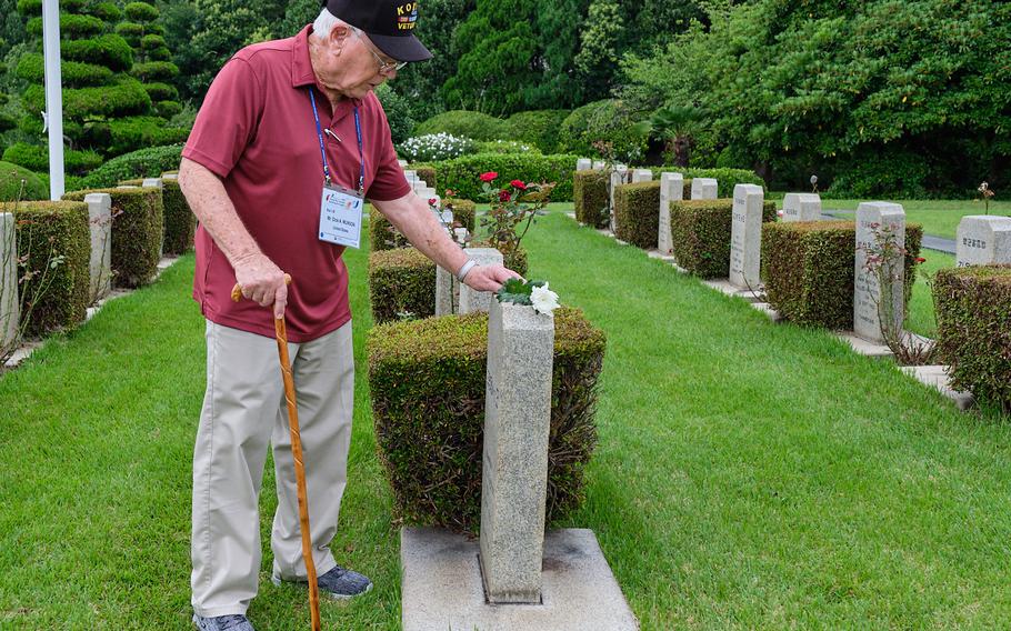 Korean War veteran Dick Munson places a flower on a headstone at the United Nations Memorial Cemetery in Busan, South Korea, Thursday, July 25, 2019.