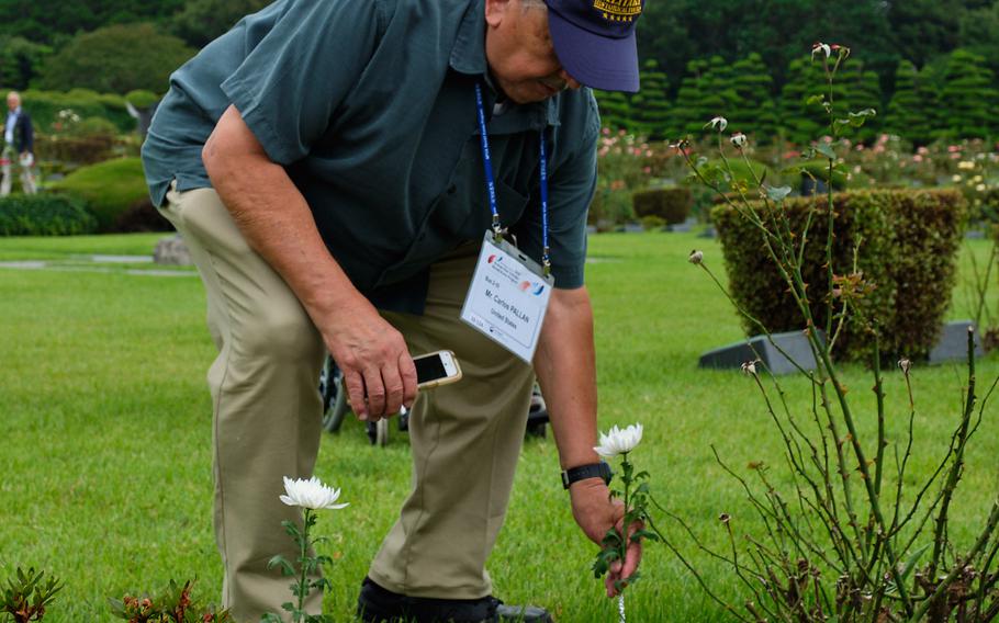 Carlos Pallan, a Korean War veteran, places a white flower on the headstones of a U.S. servicemember at the United Nations Memorial Cemetery in Busan, South Korea, Thursday, July 25, 2019.
