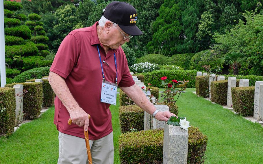 Korean War veteran Dick Munson places a flower on a headstone at the United Nations Memorial Cemetery in Busan, South Korea, Thursday, July 25, 2019.