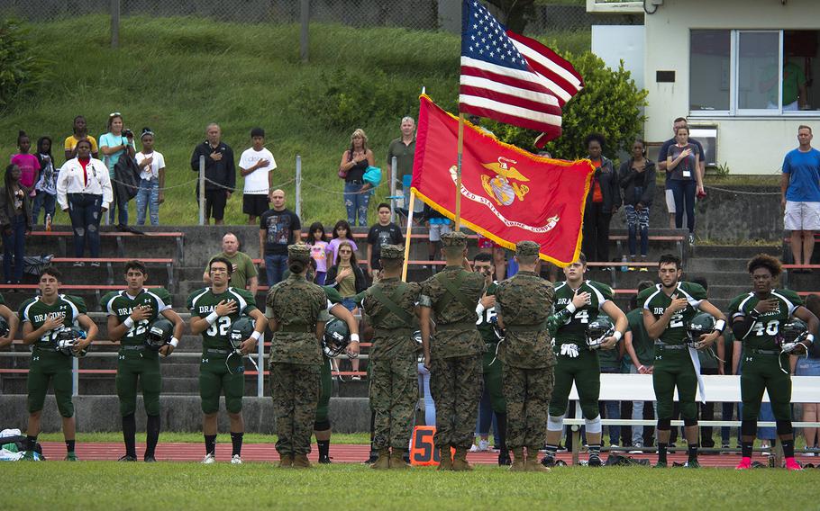 The Kubasaki Dragons salute the flag before the start of their first football game of the season against the Kadena Panthers at Mike Petty Stadium on Camp Foster, Okinawa, Japan, Saturday, Sept. 7, 2019. 