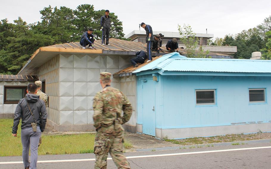 Members of the U.N. Command security battalion watch as North Koreans work on repairing damage from a typhoon earlier this month at the Joint Security Area on the Korean border.