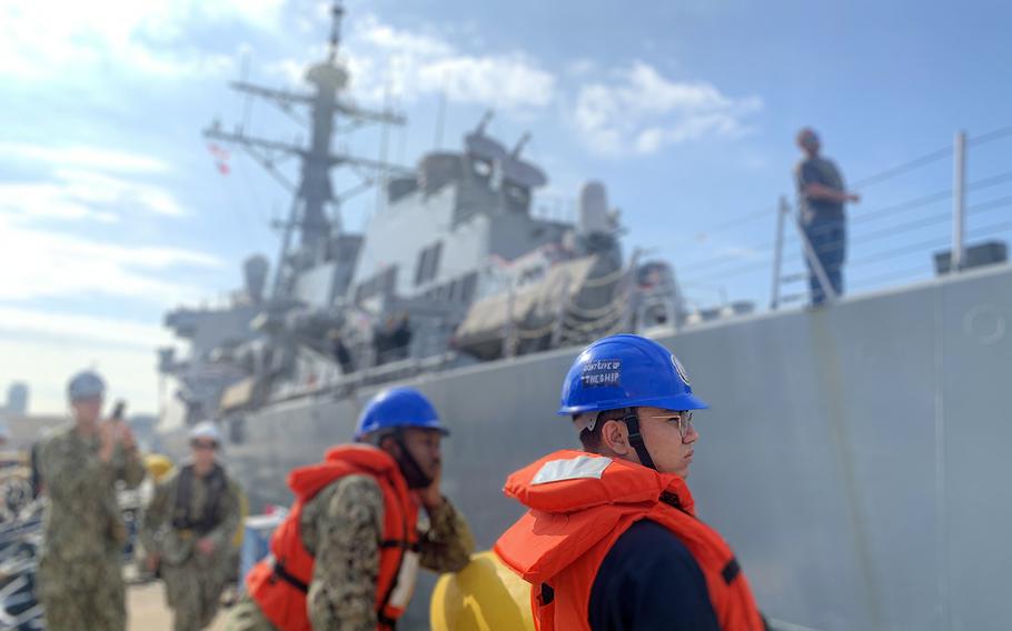 A sailor watches as the USS John S. McCain pulls away from Yokosuka Naval Base, Japan, Monday, Oct. 28, 2019. On his helmet, a blue "Don't Give Up the Ship" sticker uses the same phrase McCain sailors adopted for their flag honoring those killed in the destroyer's August 2017 collision. 