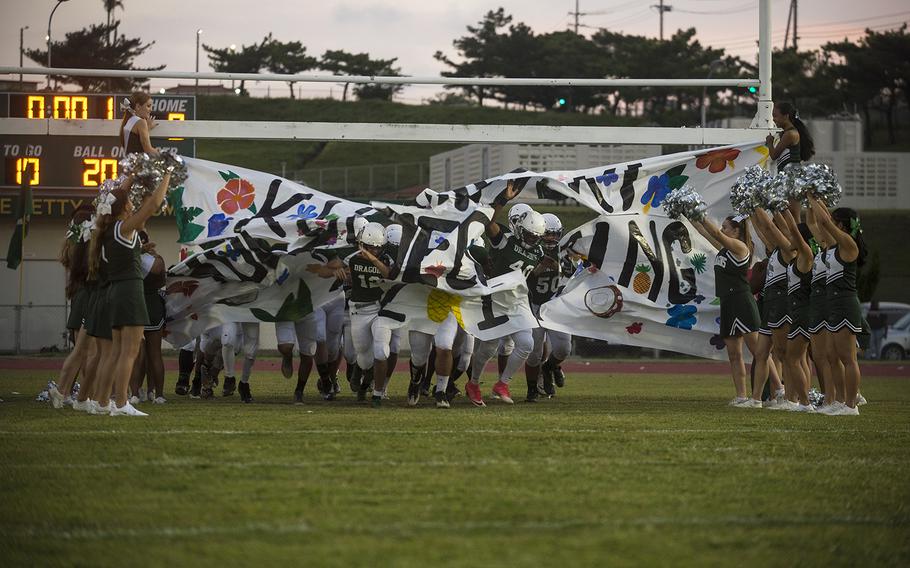 The Kubasaki Dragons sprint through a homecoming banner ahead of their game against the Camp Humphreys Blackhawks at Camp Foster, Okinawa, Friday, Oct. 25, 2019.