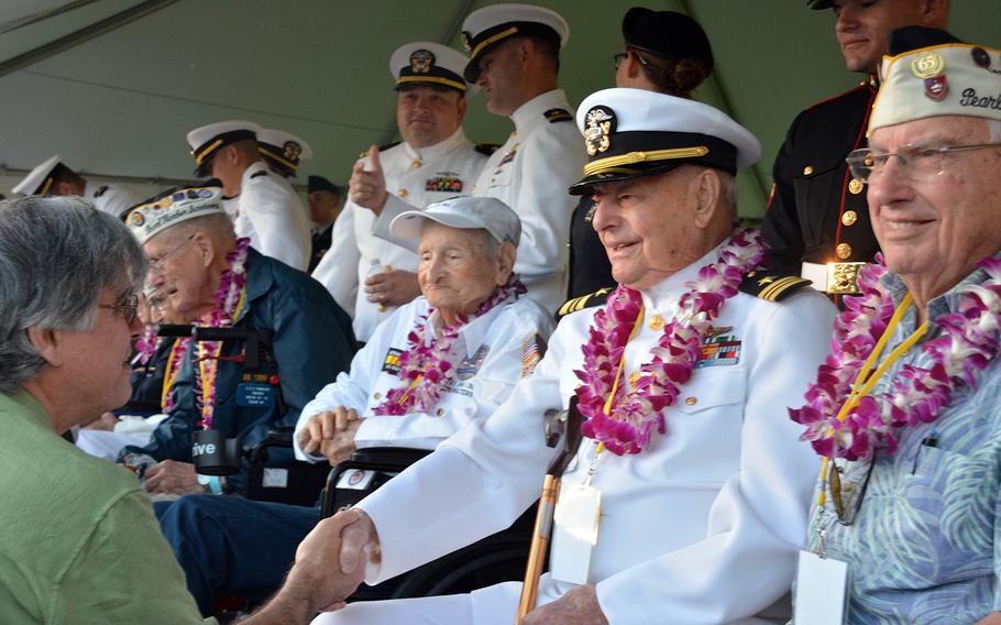 Lou Conter, shaking hands, sits with other veteran survivors of the Japanese surprise attack on Oahu before the beginning of a ceremony Dec. 7, 2019, at the Pearl Harbor National Memorial that marked the event.