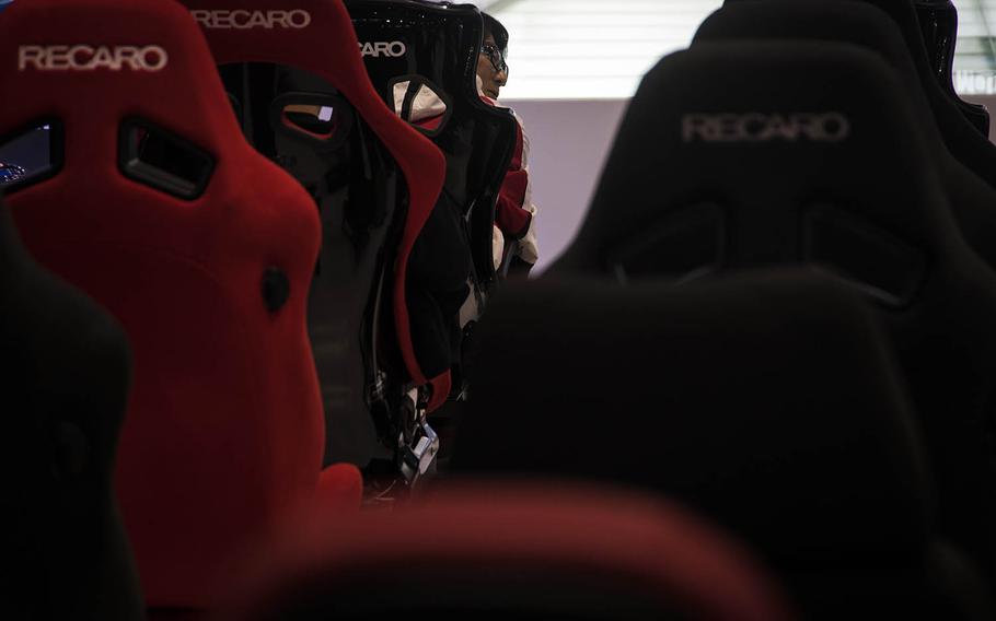 A visitor to Tokyo Auto Salon 2020 sits in a racing seat at the Recaro booth at the Makuhari Messe convention center in Chiba, Japan, Friday Jan. 10, 2020. 