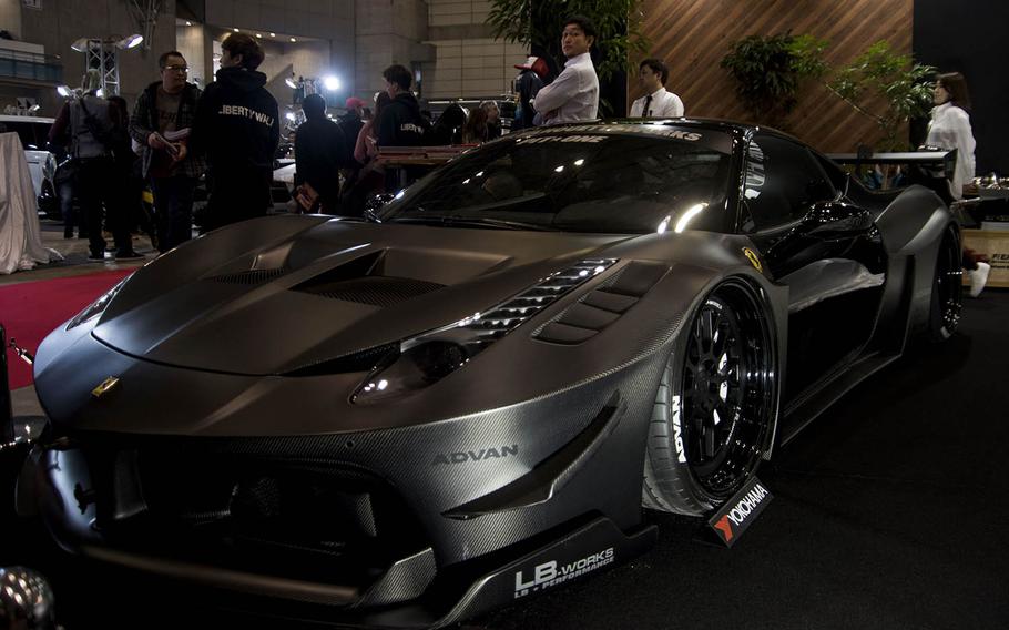 A representative for Liberty Walk LB performance leans on a Ferrari 458 sporting the company's new wide body kit at Tokyo Auto Salon 2020 in Chiba, Japan, Friday, Jan. 10, 2020. 