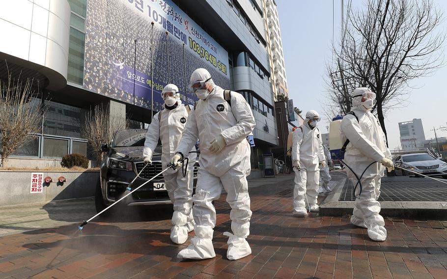 Workers wearing protective gears spray disinfectant against the new coronavirus in front of a church in Daegu, South Korea, Thursday, Feb. 20, 2020. 