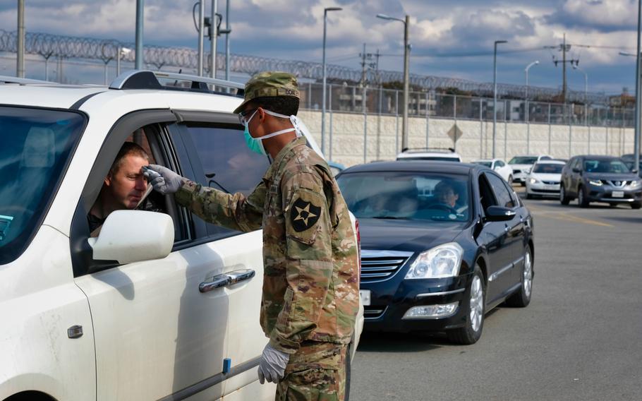 A 2nd Infantry Division soldier checks for a temperature as dozens of vehicles line up to enter the Dongchang-ri gate at Camp Humphreys, South Korea, Wednesday, Feb. 26, 2020.
