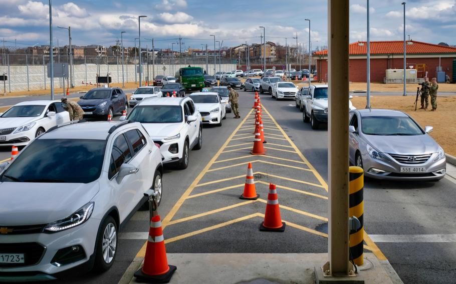 A stream of vehicles wait to enter the Dongchang-ri gate at Camp Humphreys, South Korea, Wednesday, Feb. 26, 2020, as soldiers screen visitors for the new coronavirus. 
