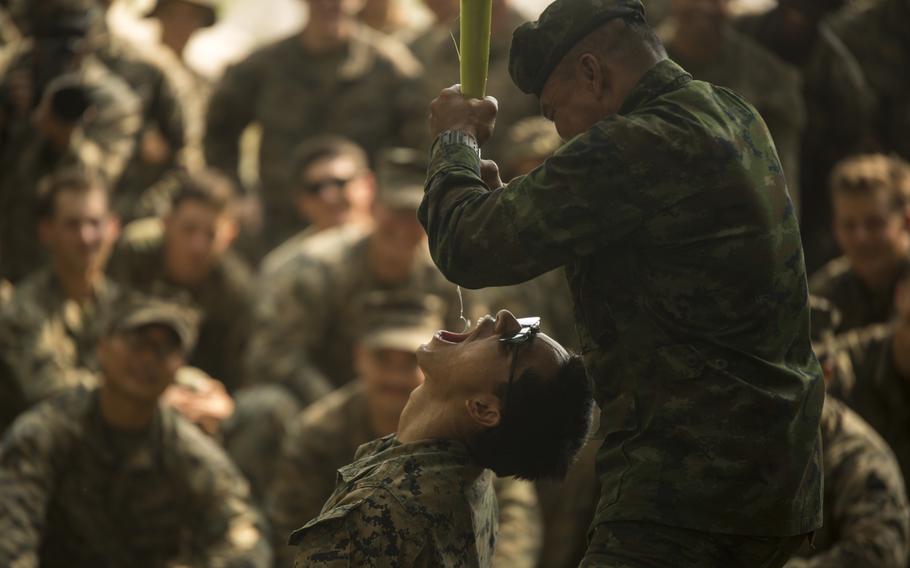 A Royal Thai Marine instructor squeezes water from a banana tree root into the mouth of a U.S. Marine with Alpha Company, Battalion Landing Team, 1st Battalion, 5th Marine Regiment, during jungle survival training as part of exercise Cobra Gold 2020 at Ban Chan Khrem, Chanthaburi, Thailand, March 2, 2020.